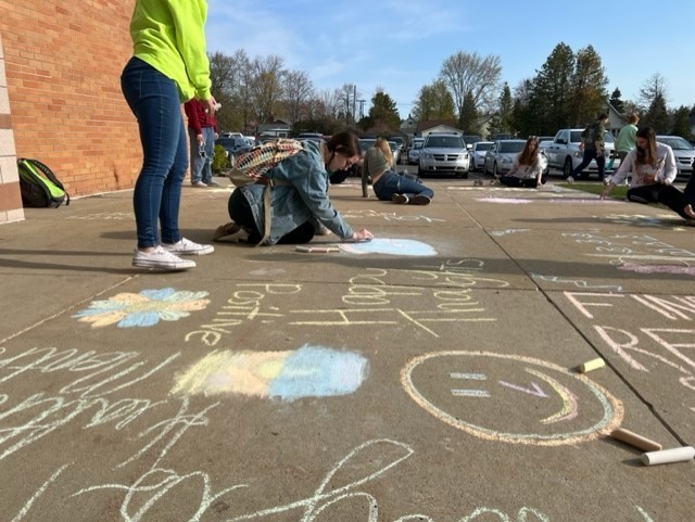 High School Students leaving positive chalk messages on sidewalk