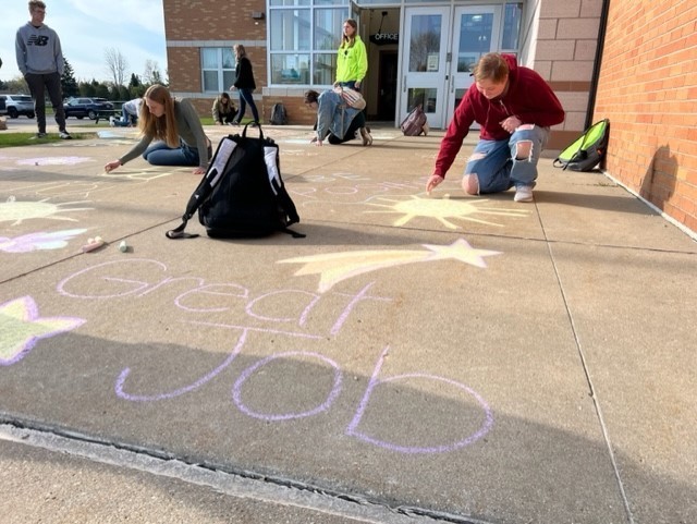 high school students with chalk messages in front of school
